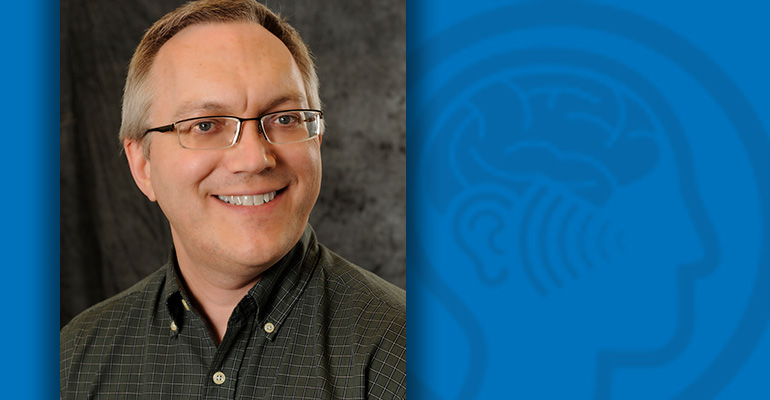 Headshot of Brett Schofield on a blue field with Hearing RFA graphic in the background