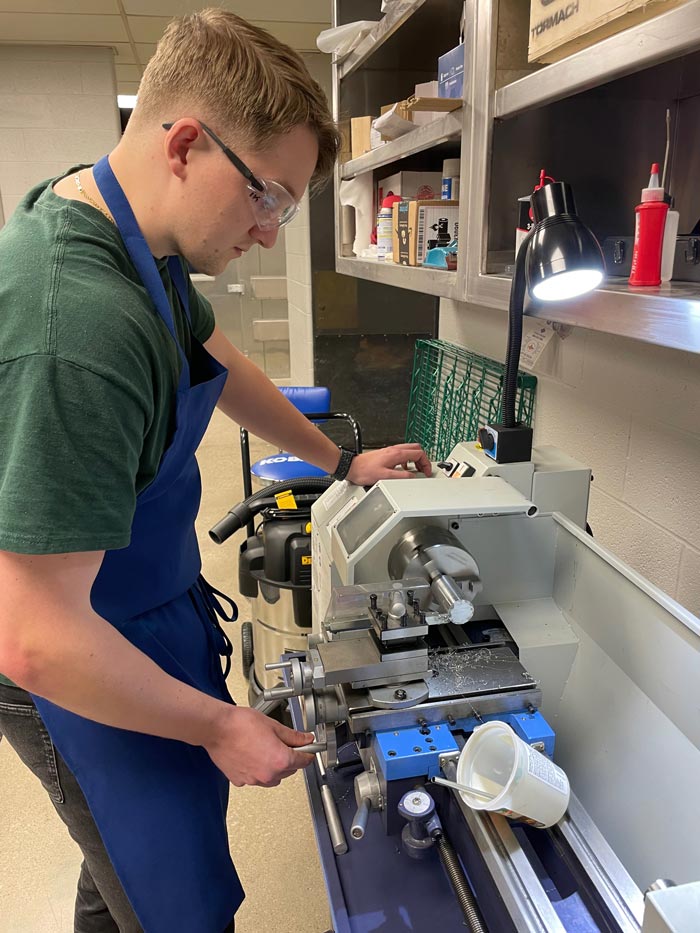 Dayton-Lathe.2 A man in safety gear uses a lathe.