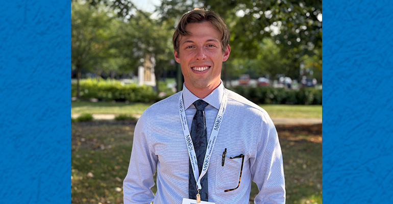 Young man wearing dress shirt and tie poses outside