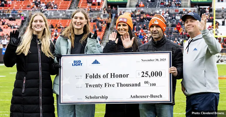 Five people holding an oversized check on the field at Cleveland Browns stadium.