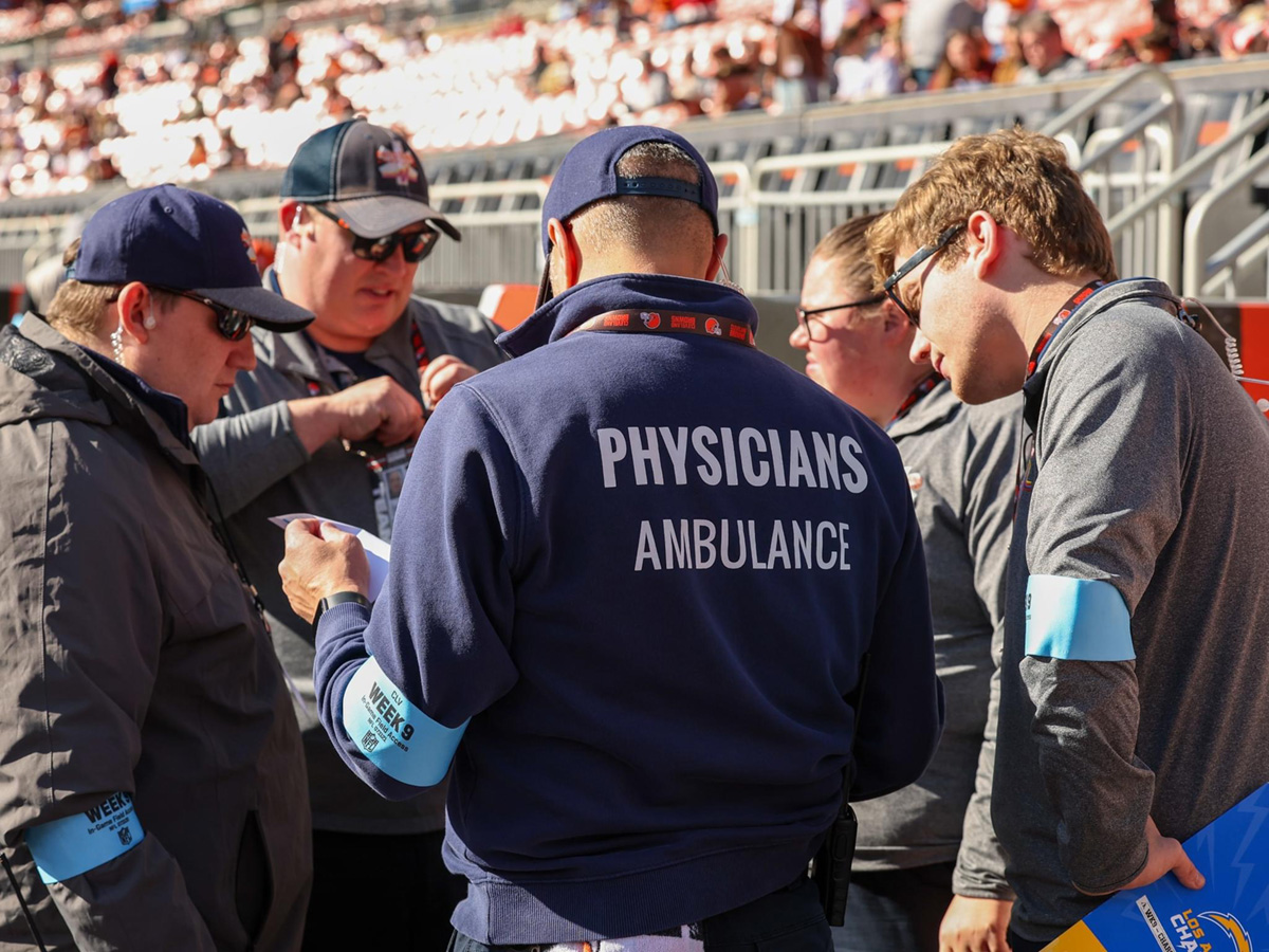 close up of a group of people wearing glasses looking down at paper at Browns stadium