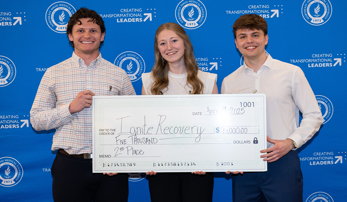 Two men and a woman pose with an oversized check