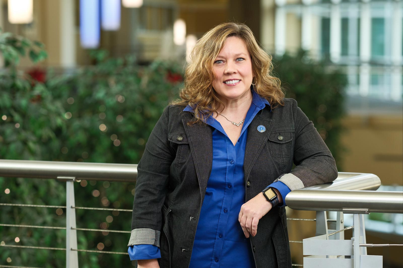 A woman in a suitjacket stands against a railing in the atrium at NEOMED.