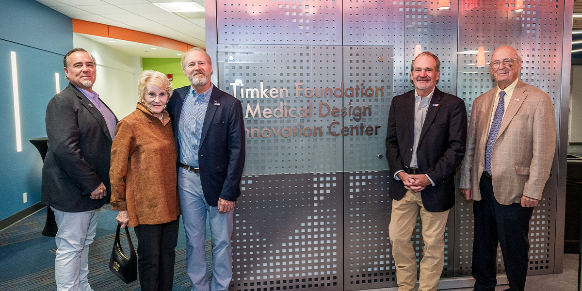 Small group of people pose in front of the MEDIC sign