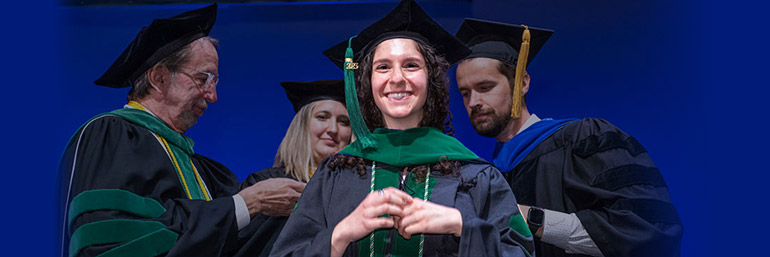 A female graduate receives her hood at commencement.