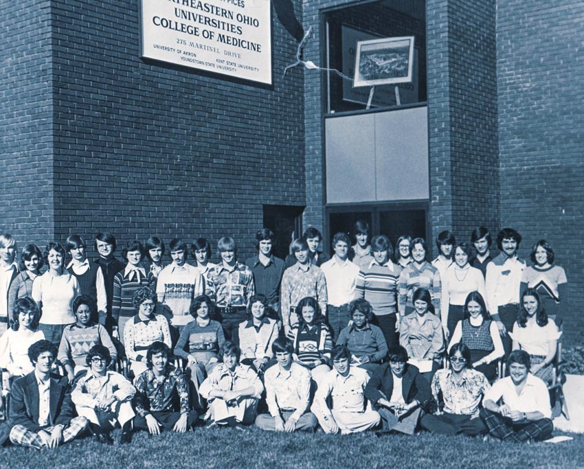 In this archive photo, a class of students sit on the grass in front of NEOMED - undated photo.