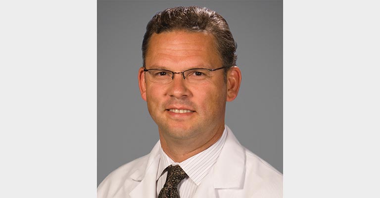 A portrait of a physician in a white coat.