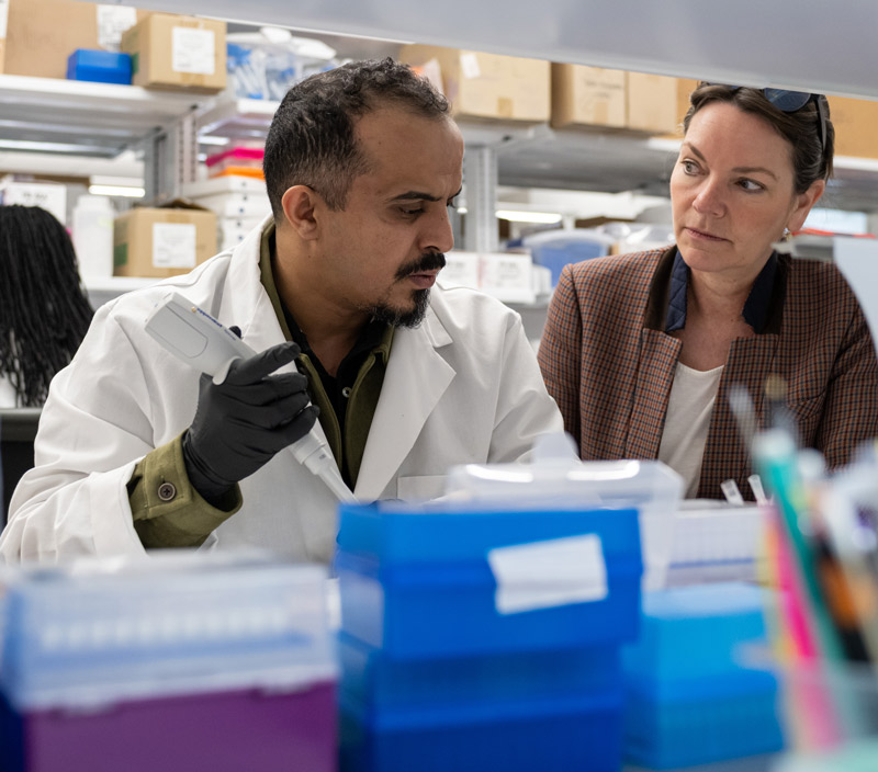 A Ph.D candidate in a white coat talks with Dr. Fleming.