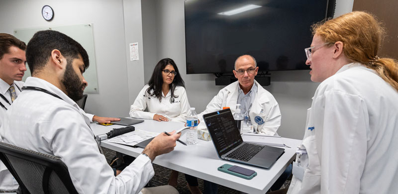 Medical students discuss cases with two preceptors at the NEOMED Free Clinic.