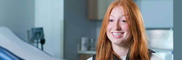 A woman in a audiology lab smiles while answering a question.