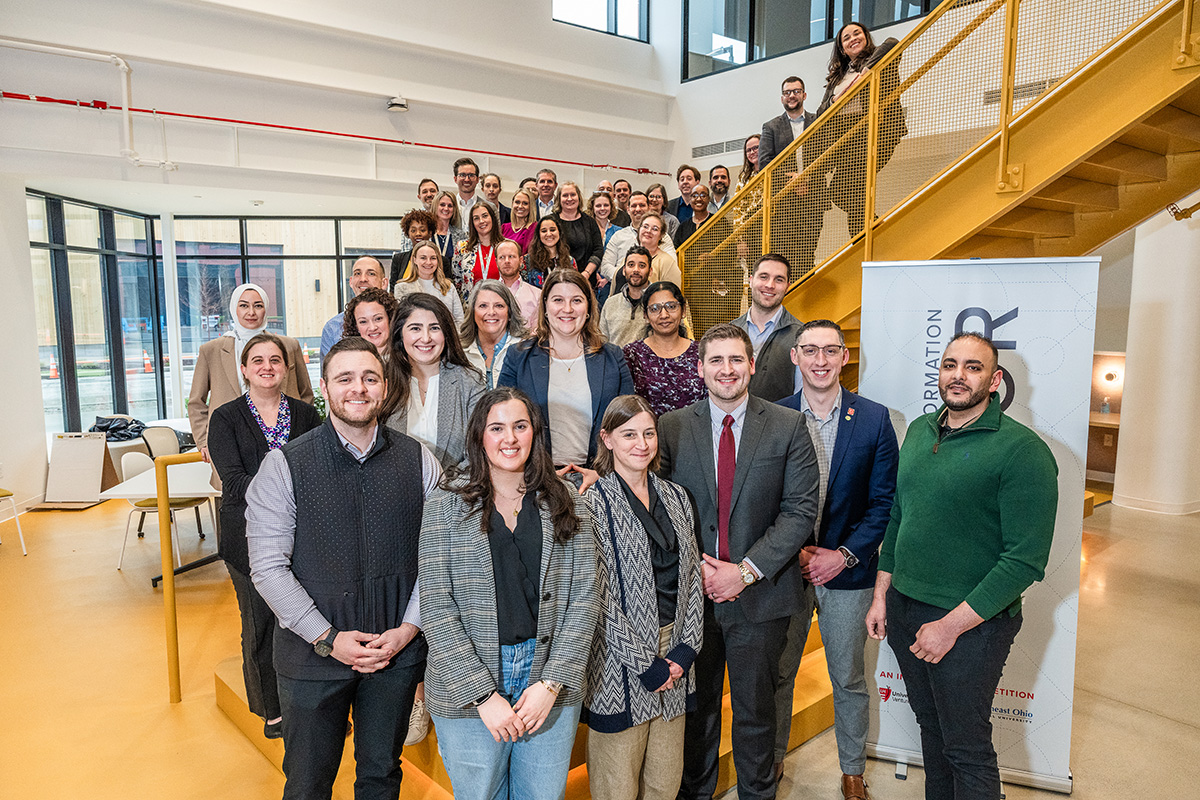 Large group of people pose winding up a staircase in a modern, open space