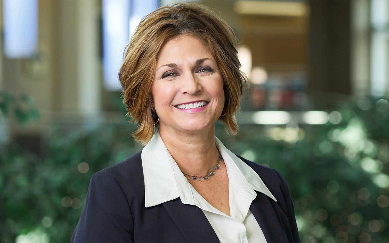A woman in a jacket stands in the bright atrium at NEOMED.