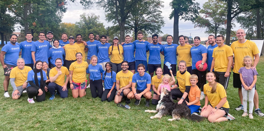 An outdoor group photo of players from the faculty vs. students kickball game.