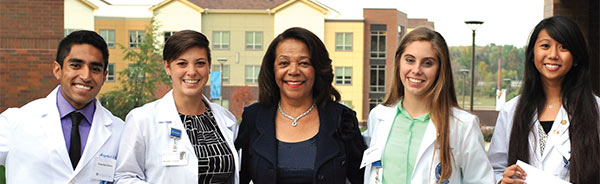 Five people in a row smiling at a camera. The woman at center is Judith Barnes Lancaster.