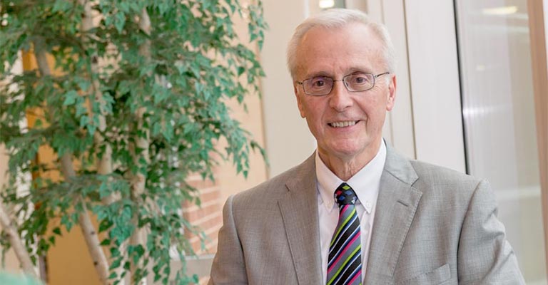 A man in a gray coat stands in an atrium.