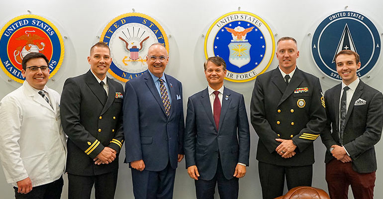 In NEOMED's new veteran's lounge, six men stand in front of seals representing the four branches of the military.