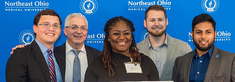 A group of people holding a large, cardboard check that they won.