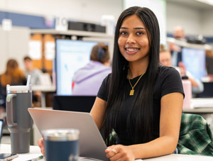 A pharmacy student works on a laptop in a large classroom at NEOMED.