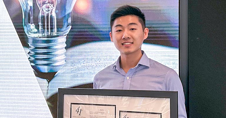 A medicine student holds his first-place prize.