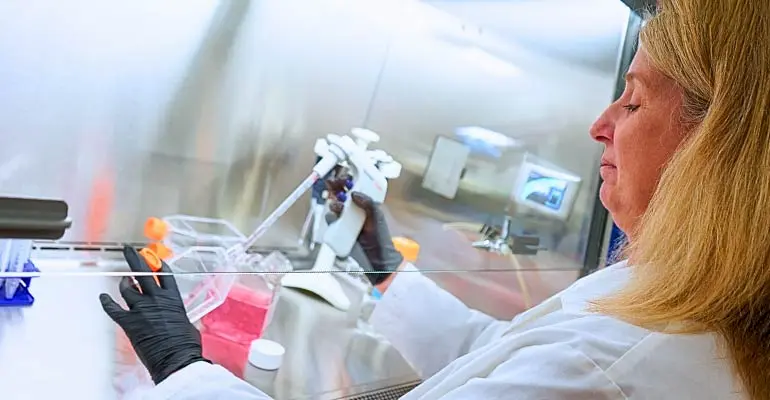 A woman in a white coat mixes chemicals in a lab at NEOMED.