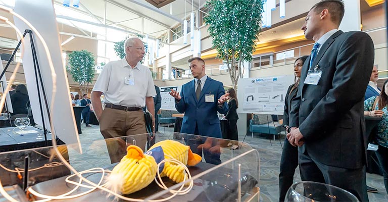 Two medicine student explain their invention to a judge.
