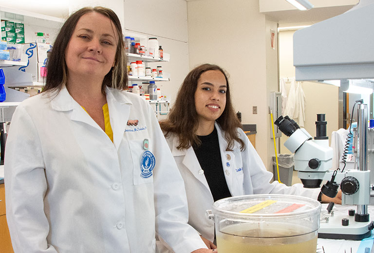 Two researchers in white coats in their lab at NEOMED.