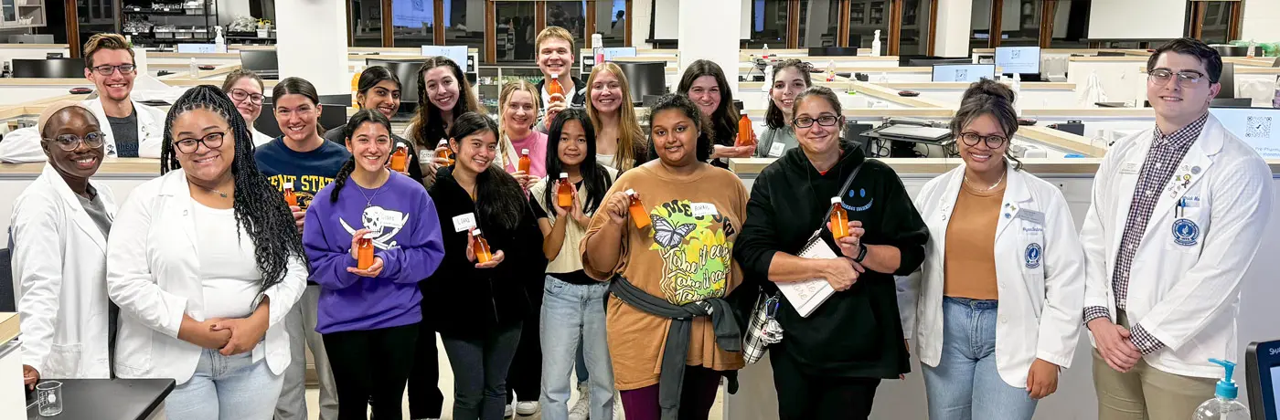 A group photo of students in the club, many of which are wearing white coats.