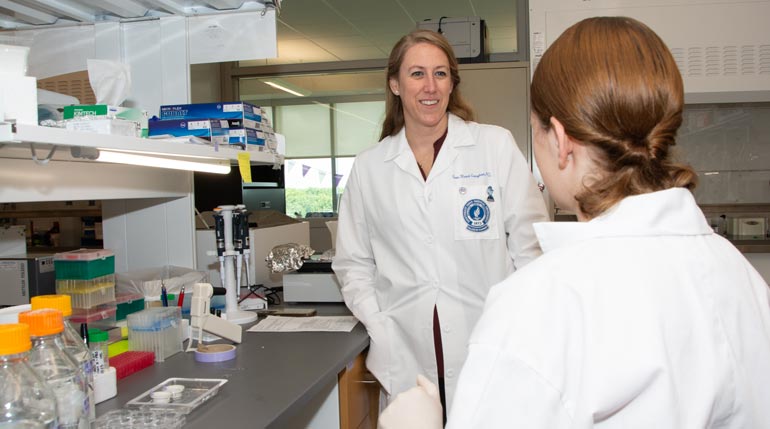 Two researchers in white coats in their lab at NEOMED.