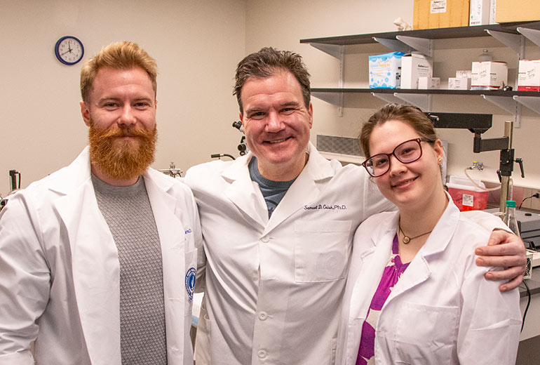 Three researchers in white coats in their lab at NEOMED.