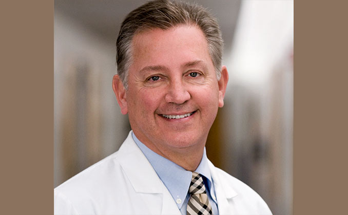 A man in a white coat in a hospital cooridor.