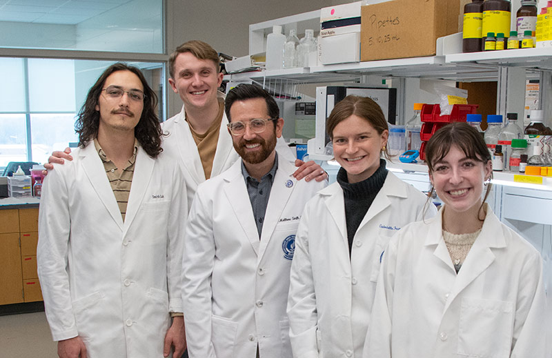 Matthew Smith, Ph.D., and researchers in white coats in their lab at NEOMED.