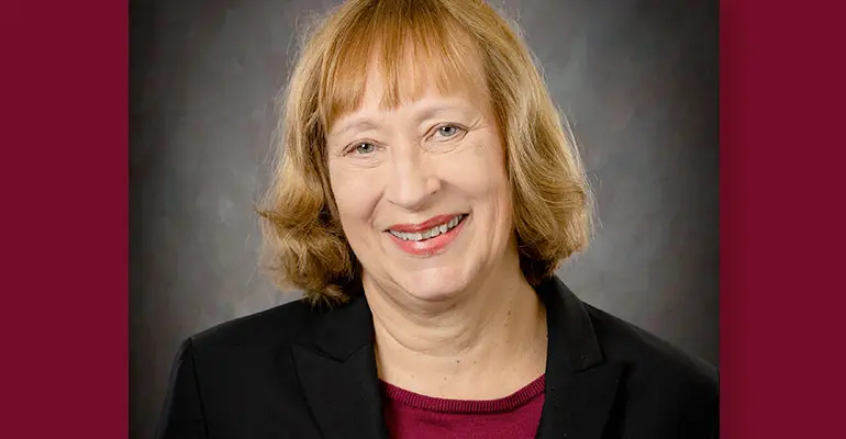 A woman in a black coat against a gray background.