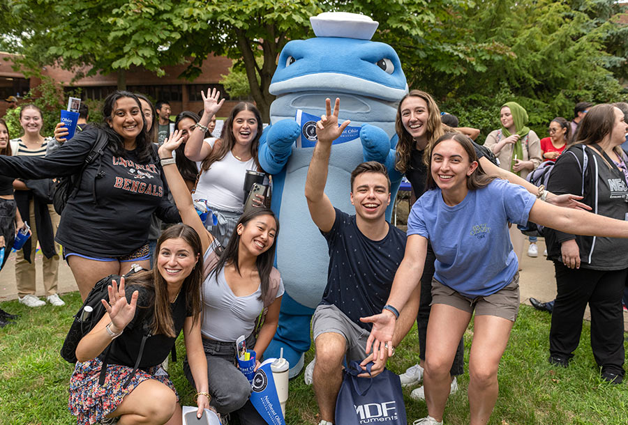 Students pose with the campus mascot, a costumed whale.