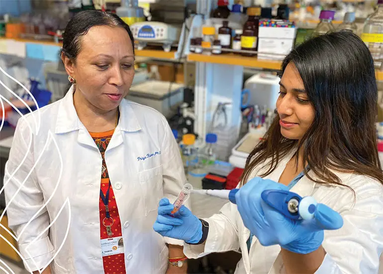 Two NEOMED researchers in white coats in a lab.