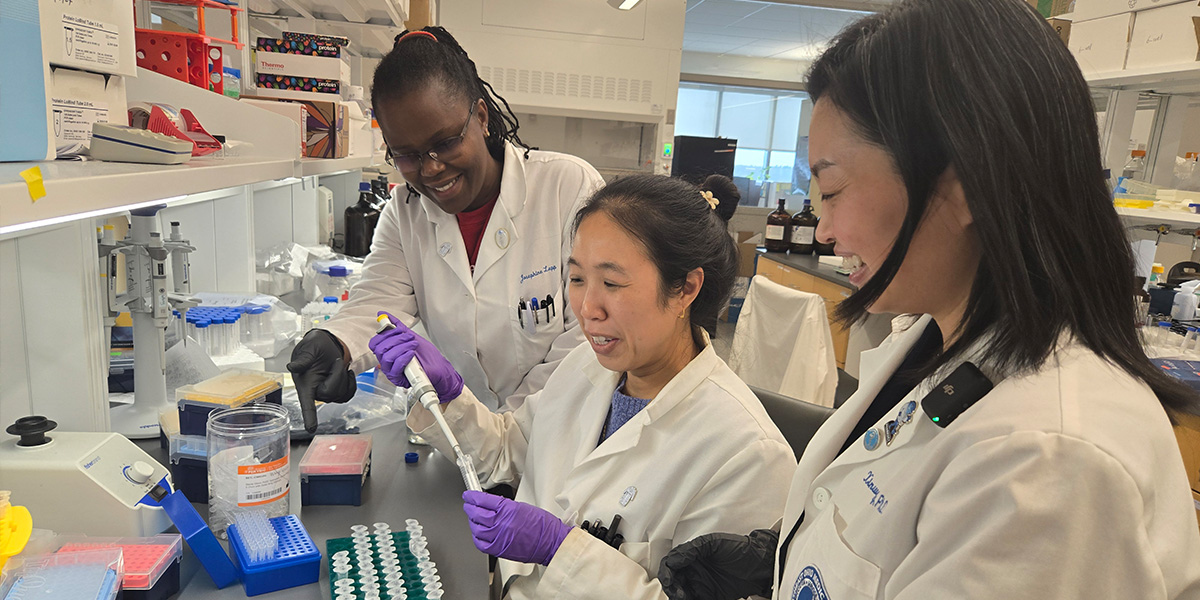 Three women in lab coats in a pharmaceutical sciences lab