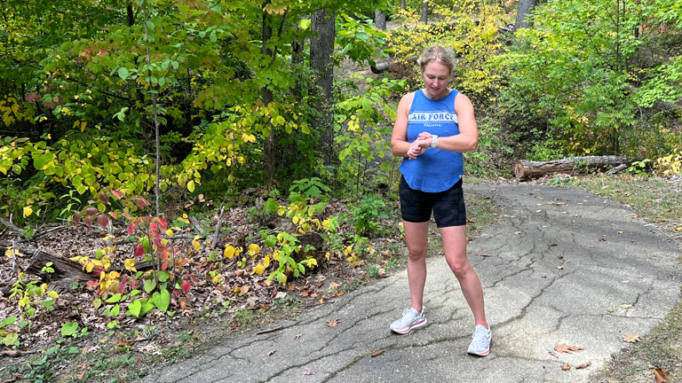 A woman in running gear starts the timer on her watch.